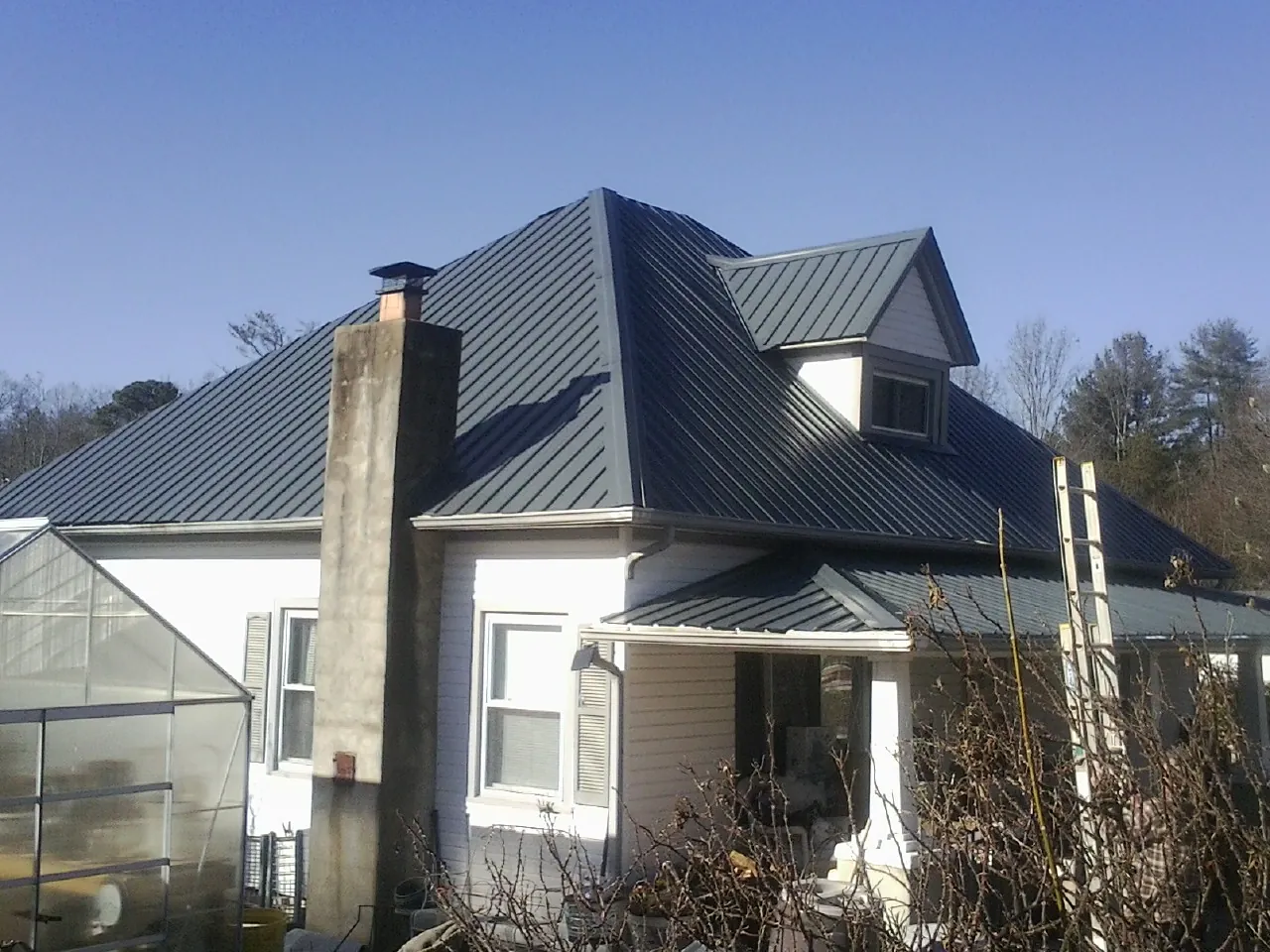 Dark blue standing seam metal roof on a white farmhouse with dormer — Slate & Tile Roof Repair by Roofing Brothers in Sewanee