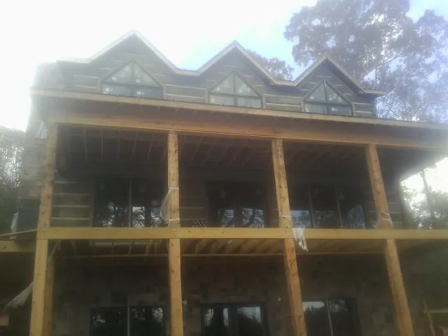 Dormers and porch framing on a large log home under construction — Roof Coating work by our crew in Sewanee