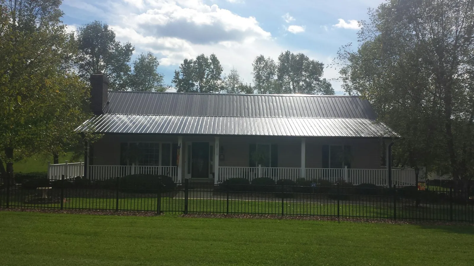 Gray metal roof on a brick ranch with a full width front porch — Gutter Guard Installation work by our crew in Sewanee