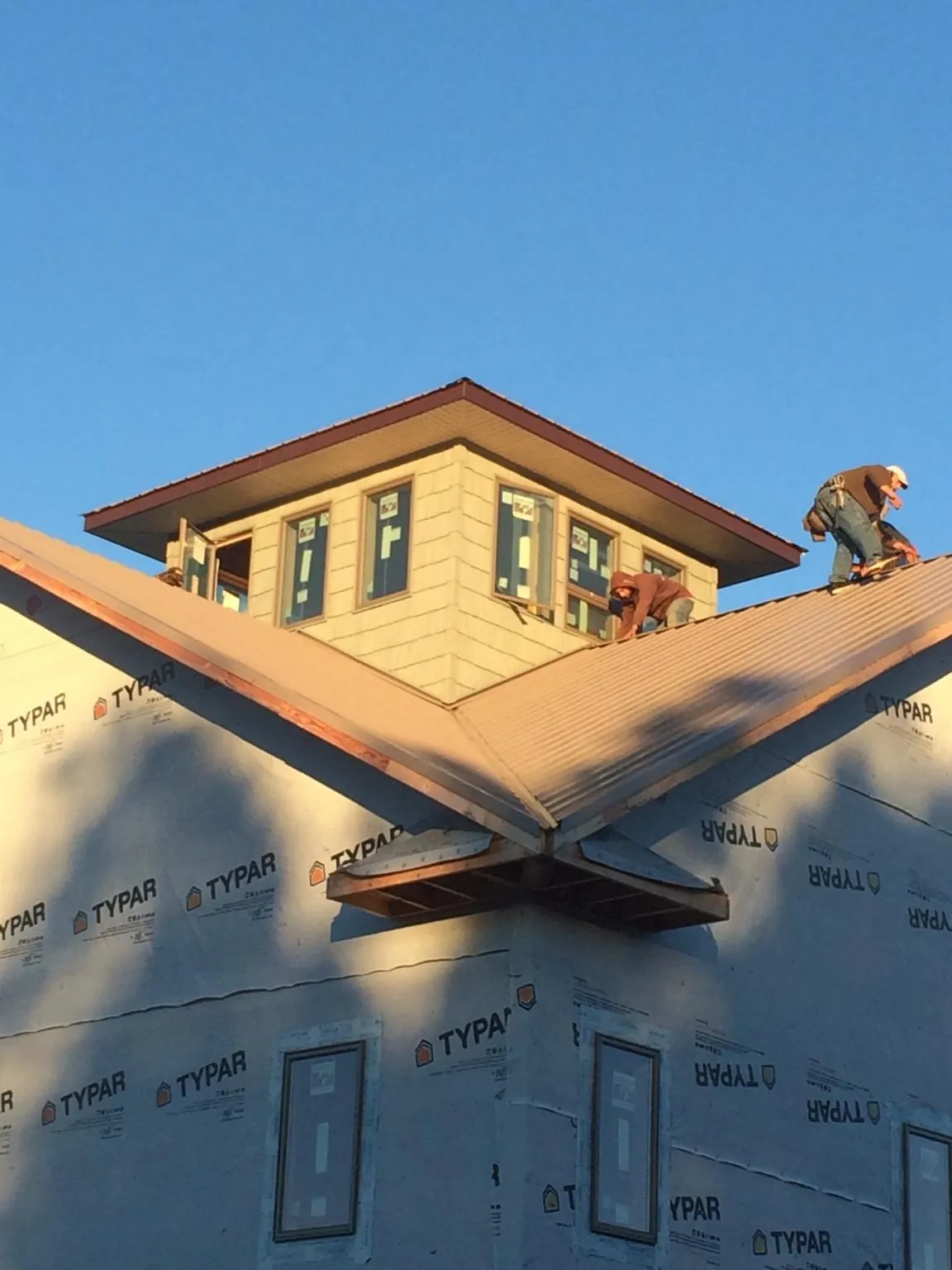 Roofers working around a rooftop cupola on a new metal roof at sunset — Roof Waterproofing in Sewanee by Roofing Brothers